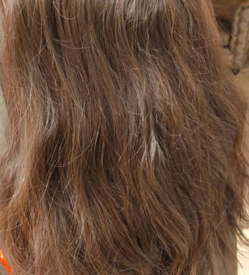 縮毛矯正の施術前。うねりと広がりのあるブラウンのロングヘアの背面